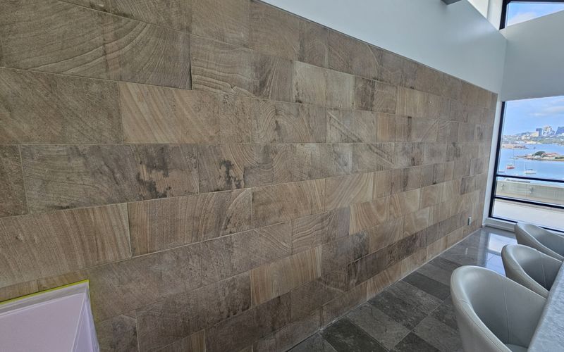 Dark damp staining patches on an interior sandstone-clad wall