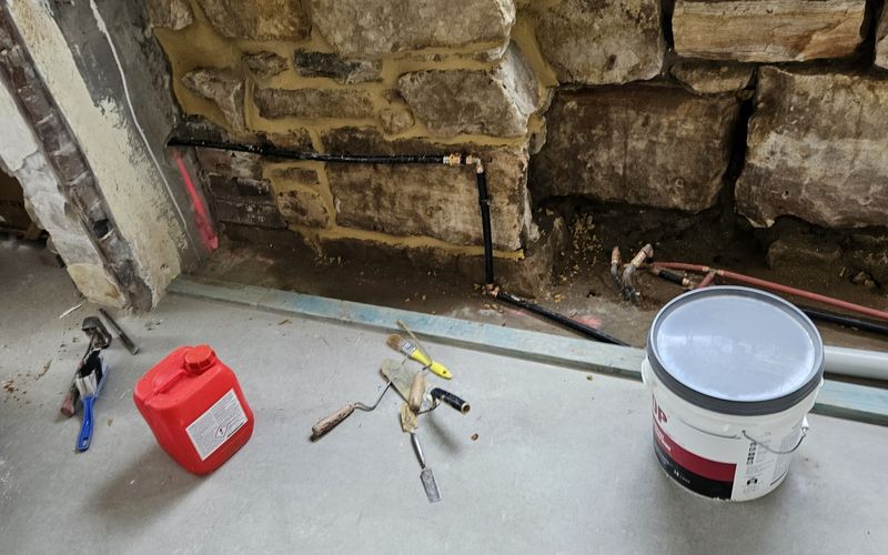 Salt-damaged sandstone foundation wall with deteriorated mortar during damp treatment work